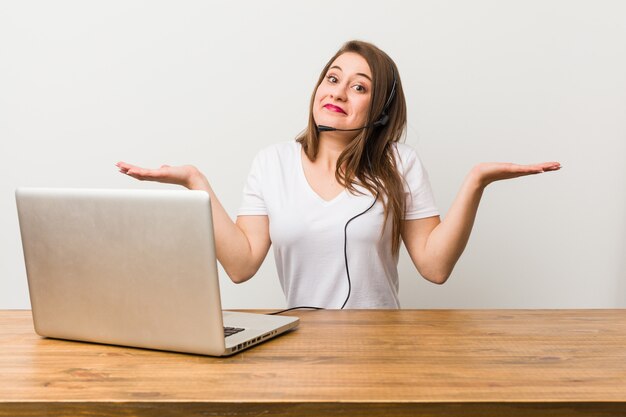 Femme jeune télémarketing doutant et haussant les épaules en geste de questionnement.