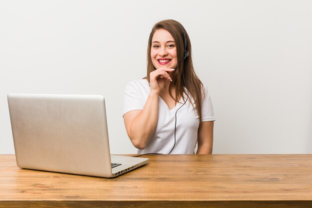 Femme jeune télévendeur souriante heureuse et confiante, toucher le menton avec la main.