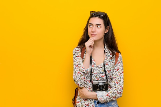 Photo femme jeune voyageur brune regardant sur le côté avec une expression douteuse et sceptique.