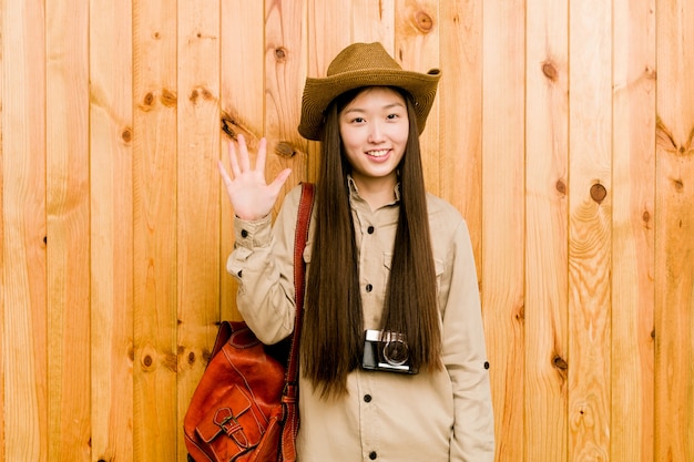 Femme jeune voyageur chinois souriant joyeux montrant le numéro cinq avec les doigts.