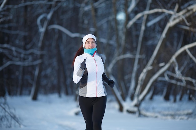 Femme jogging sur la forêt d'hiver