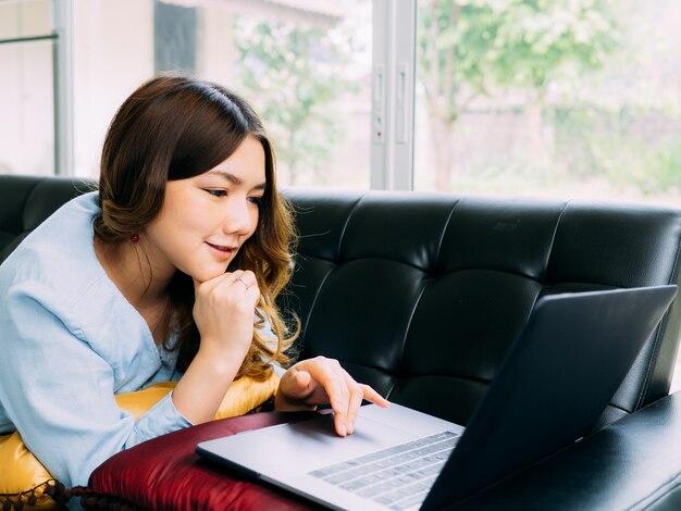 Femme jolie asiatique Internet travaille en ligne à la maison et se détendre style de vie avec son labtop