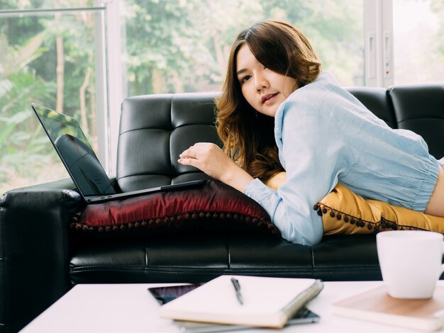 Femme jolie asiatique Internet travaille en ligne à la maison et se détendre style de vie avec son labtop