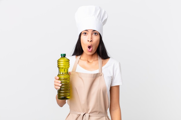 Femme jolie chef hispanique tenant une bouteille d'huile d'olive.