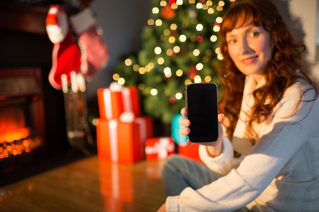 Femme jolie rousse vous montrant votre téléphone mobile