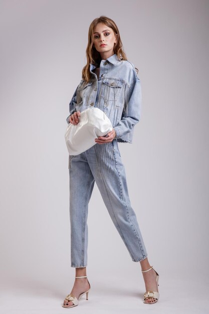 Femme en jolie veste oversize en jean denim avec sac à main pantalon strass sur fond blanc