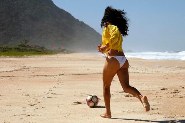 Femme jouant au ballon sur la plage