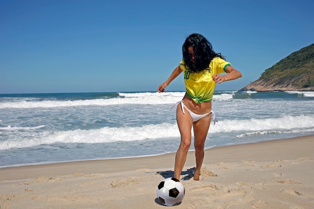 Femme jouant au ballon sur la plage