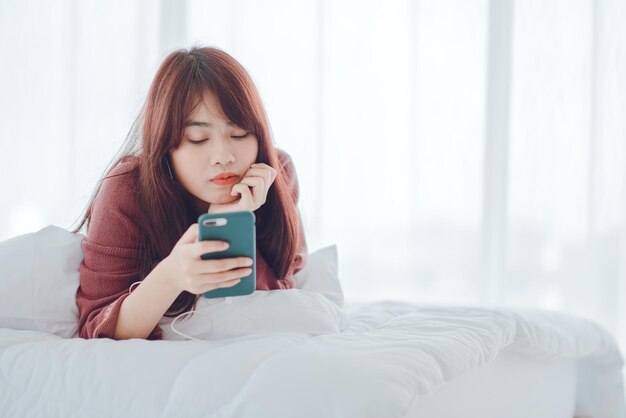 Une femme jouant au téléphone dans le lit de la maison