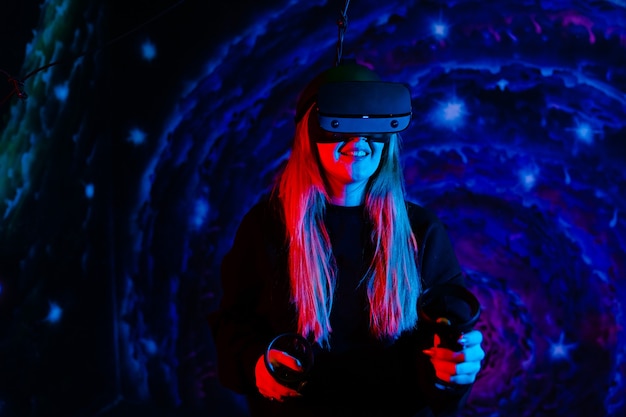 Femme jouant émotionnellement interagit avec un casque virtuel avec éclairage bleu rouge