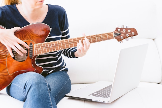 Femme jouant de la guitare à côté de l'ordinateur portable