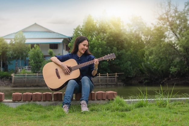 Femme jouant de la guitare l'été en plein air