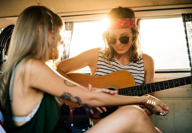 Femme jouant de la guitare sur le voyage avec des amis ensemble