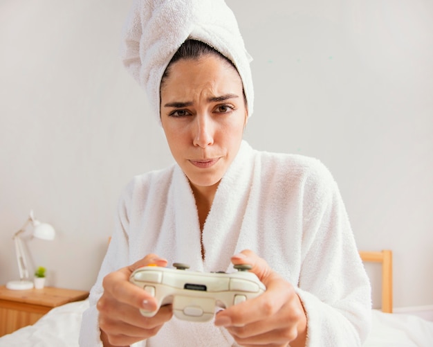 Femme jouant à des jeux vidéo à la maison après le bain