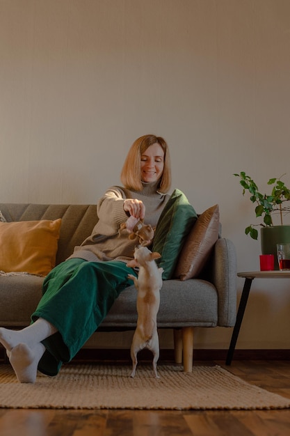 Femme jouant avec un petit chien assis sur un canapé