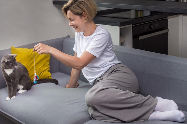 Femme jouant avec son chat sur le canapé