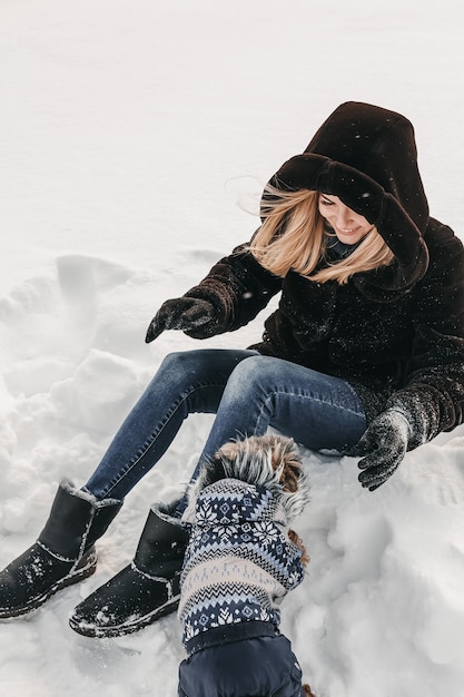 Femme jouant avec son chien dans la neige.