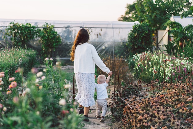 Femme jouant avec son enfant dans une serre avec des fleurs.