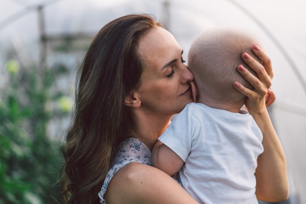 Femme jouant avec son enfant dans une serre avec des fleurs.