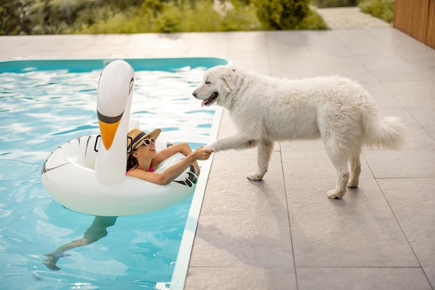 Photo une femme joue avec un chien en nageant à la piscine.