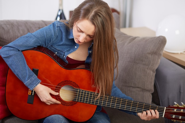 Femme joue de la guitare à la maison