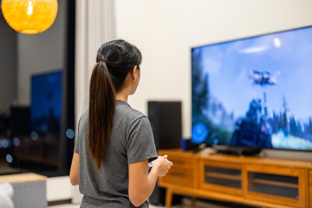 Une femme joue à un jeu vidéo à la télé à la maison.