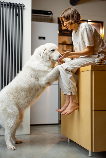 Une femme joue avec son chien dans la cuisine à la maison