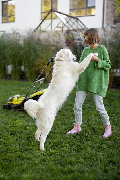 Une femme joue avec son chien dans son jardin tout en jardinant