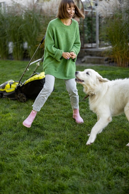 Une femme joue avec son chien dans son jardin tout en jardinant