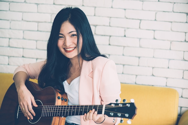 Femme, jouer guitare, sur, sofa