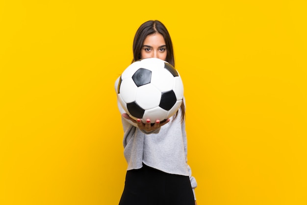 Femme de joueur de football jeune sur mur jaune isolé