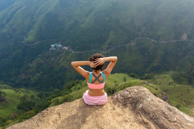 femme jouit d'une vue sur la montagne en se tenant debout sur une falaise