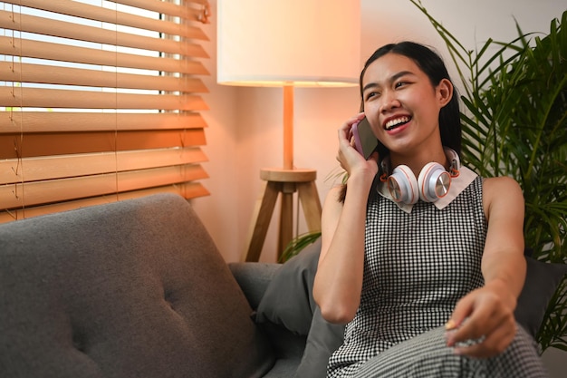 Femme joyeuse assise dans le salon et parlant sur un téléphone portable