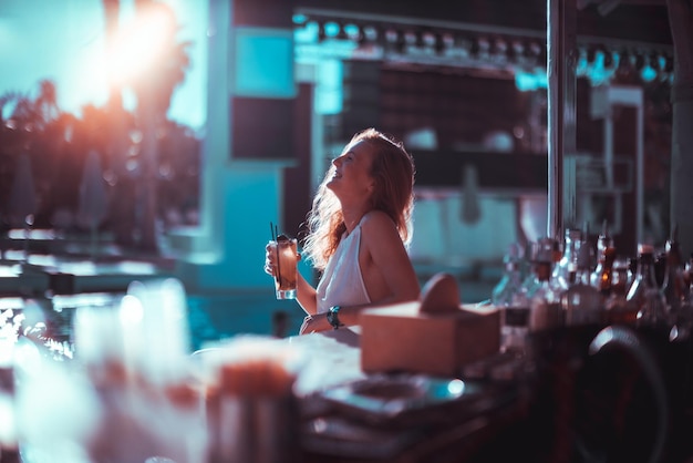 Une femme joyeuse assise avec un verre au coucher du soleil