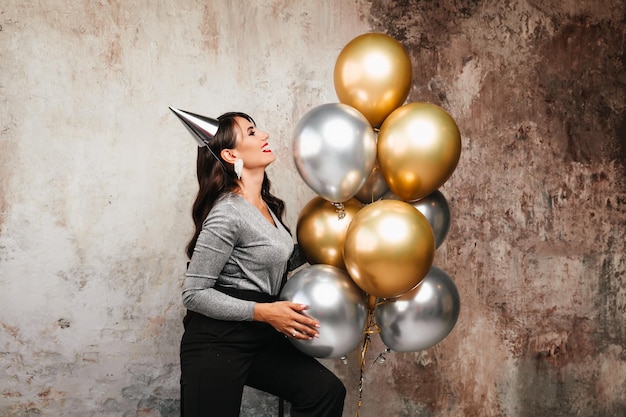 Une femme joyeuse avec des ballons rit une jeune brune aux cheveux longs célèbre son anniversaire des ballons à l'hélium