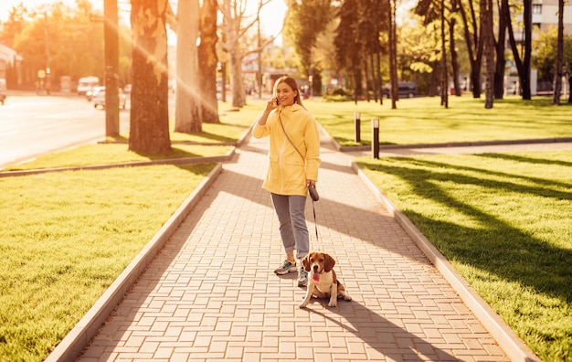 Femme joyeuse avec un chien parlant au téléphone dans le parc