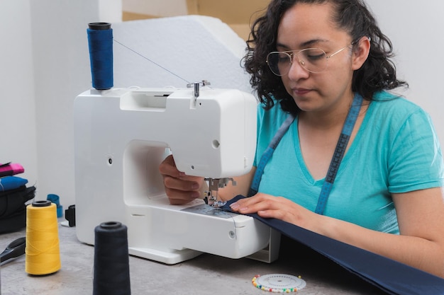 Femme joyeuse cousant assise sur son lieu de travail dans un atelier de mode