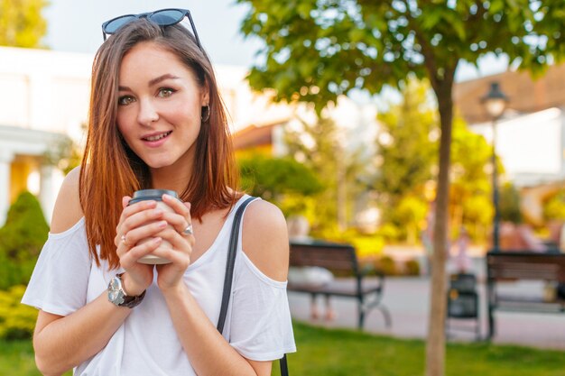 Femme joyeuse dans la rue en buvant du café du matin