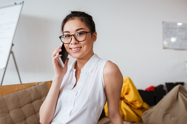 Femme joyeuse dans des verres, parler au téléphone mobile