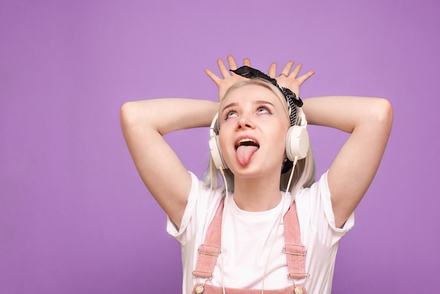 Femme joyeuse dans des vêtements légers et des écouteurs fait la grimace