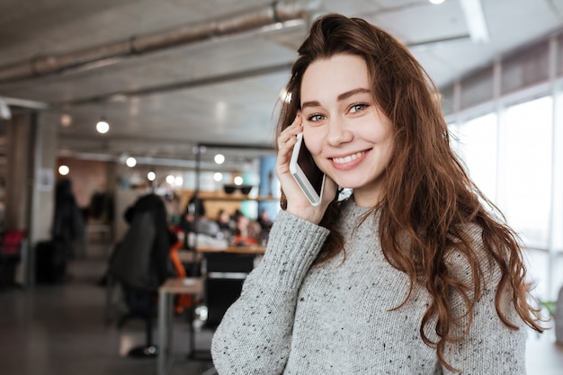 Femme joyeuse debout et talkign sur téléphone mobile