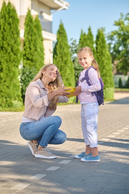 Femme joyeuse donnant une boîte à lunch à une petite fille