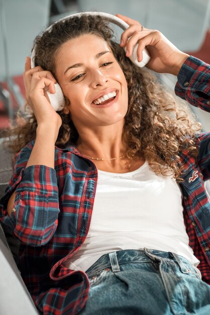 Photo une femme joyeuse écoutant de la musique sur le canapé.