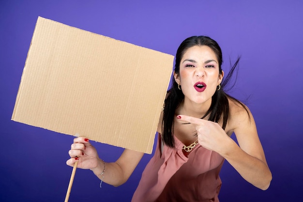 Une femme joyeuse et excitée pointe vers une enseigne avec sa main sur un fond de velours violet isolé