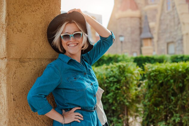 Femme joyeuse et joyeuse vagabonde avec des lunettes de soleil à la mode lors d'un voyage à l'étranger en été
