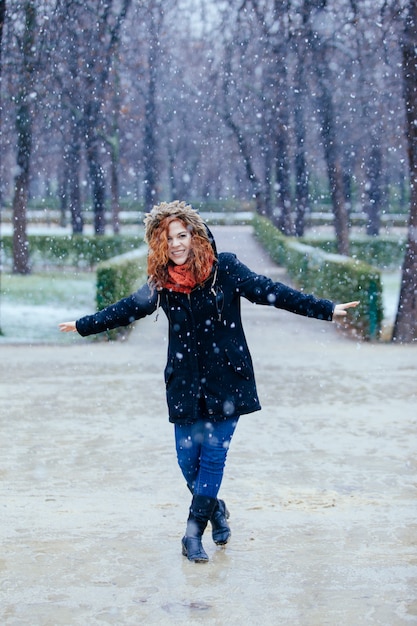 Femme joyeuse marchant sous la neige