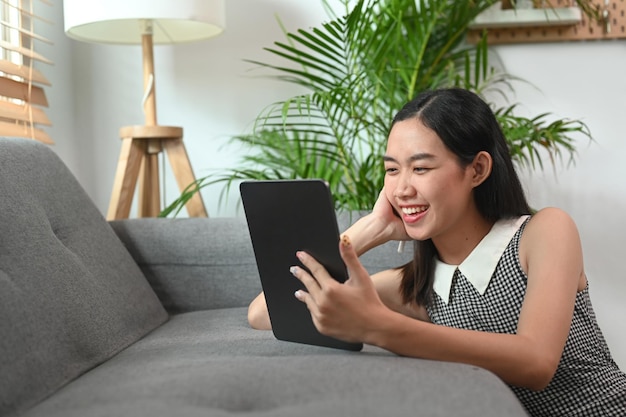 Femme joyeuse naviguant sur Internet avec table numérique à la maison