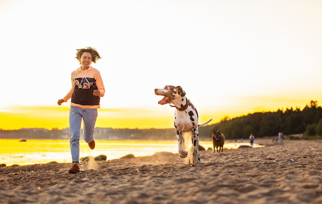 Femme joyeuse passant du temps à courir avec des chiens sur une plage de sable
