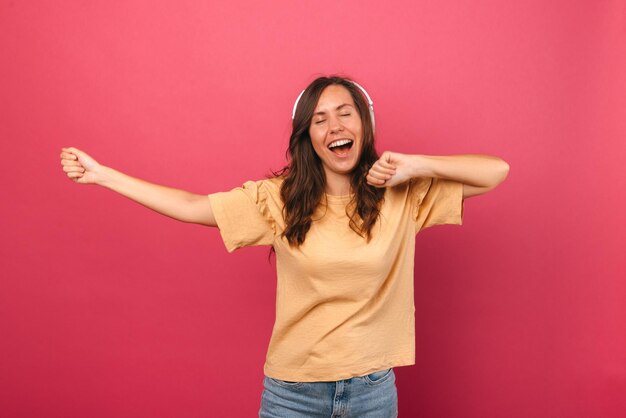 Une femme joyeuse portant des écouteurs s'amuse les yeux fermés en dansant