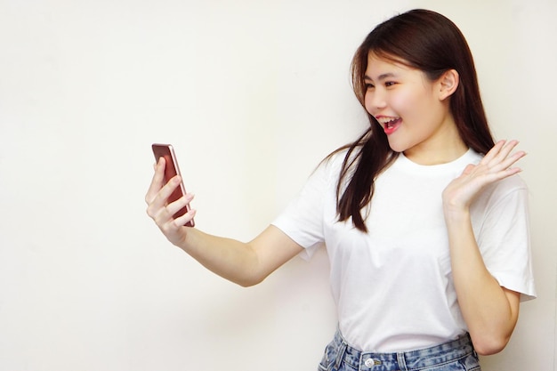 Une femme joyeuse portant des t-shirts blancs et tenant un téléphone